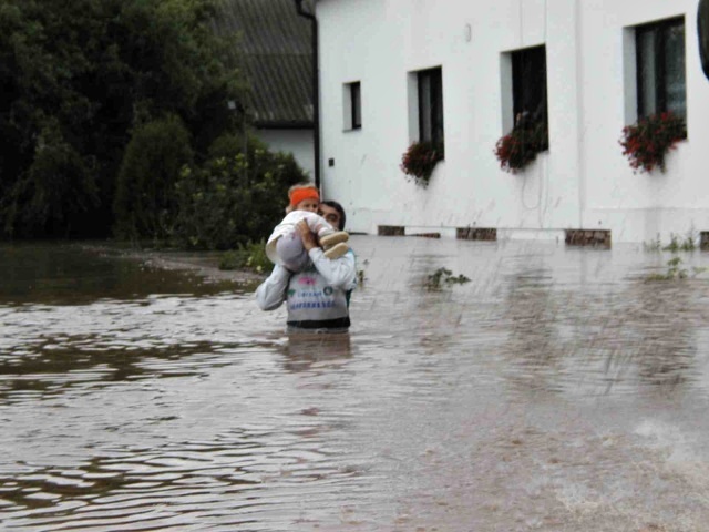 Pan Mašek nese do záchranného vozu vlastní dítě. Fotografie byly pořízeny 13.8.2002 – 10 hodin.